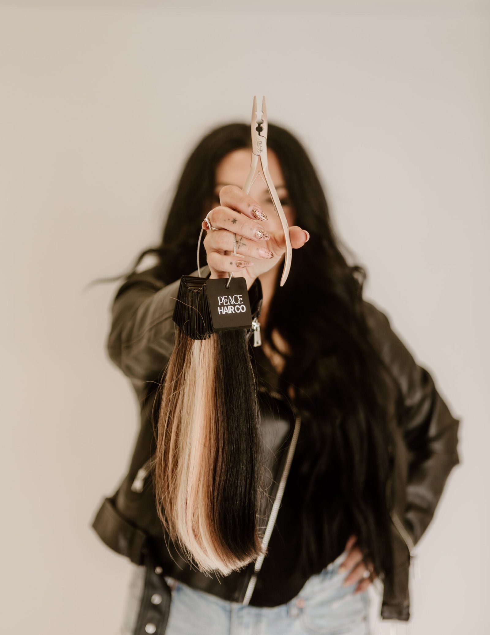 EA7A5792-2 | Rawe Beauty A picture of Morgan, owner of Rawe beauty. She has long lback hair and is standing with her back to the camera holding hair extensions in her hand.