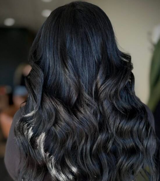 Picture of a woman with long flowing black hair, with her back to the camera, demonstrating hair extensions