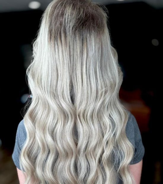 Picture of a woman with long wavy blonde hair, with her back turned to the camera, to illustrate hair coloring techniques