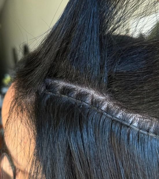 Picture of a woman with black hair, having hair extensions sewn into her hair
